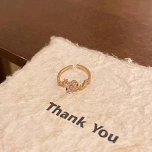 Close-up of adjustable gold butterfly ring with pink zircon on decorative paper