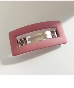 Detail view of pink matte hair clip featuring silver metal spring clamp on white background