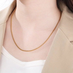 Close-up of a minimalist golden stainless steel basket chain necklace on a model's neck