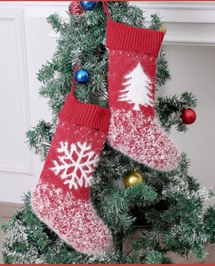 Detail view of red knitted Christmas stockings with snowflake patterns on festive tree