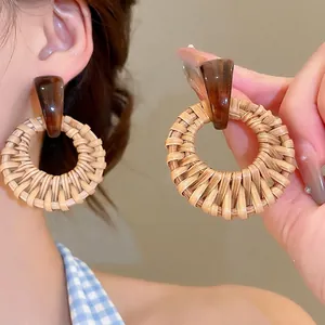 Bohemian style woven straw hoop earrings with tortoiseshell acrylic studs on model