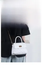 Detail of white quilted chain bag featuring elegant gold metal twist lock and luxury texture