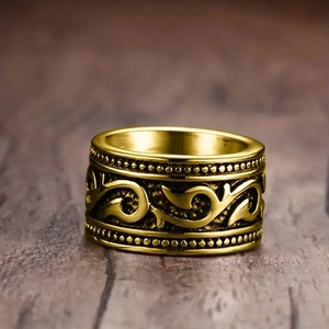 Macro shot of vintage gold wide-band ring with intricate floral carvings on wood background