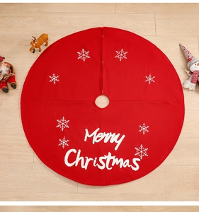 Detail of red Christmas tree skirt with white embroidered snowflakes and festive motifs