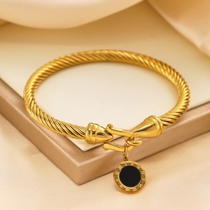 Detailed shot of gold-plated twisted bangle with roman numeral engraved black disc pendant