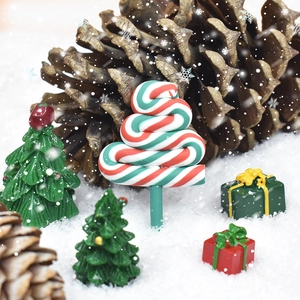 Close-up of candy-striped Christmas tree resin ornament in a festive snow scene setup