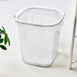 Modern transparent striped trash can with white rim on a beige carpet background
