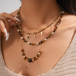 Close-up of layered bohemian tiger eye stone necklace with sun and star pendants