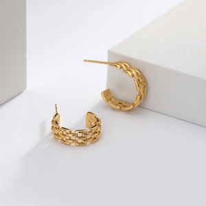 Close-up of golden S925 sterling silver twist woven C-shaped hoop earrings on white stone