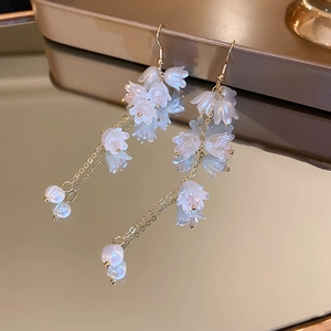 Vue détaillée des boucles d'oreilles muguet avec perles sur un plateau miroir chic