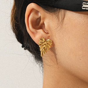 Close-up of a model wearing a heart-shaped leaf earring in polished 18k gold finish