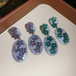 Close-up of vintage oval drop earrings with purple and green zircon floral patterns