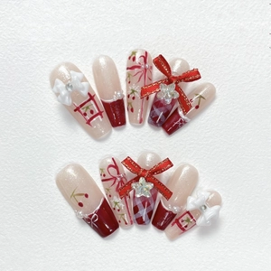 Handmade Christmas press-on nails with red bows, cherry patterns and pearl accents