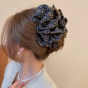 Chouchou élégant en tissu à motifs de cœurs dorés porté sur une coiffure en chignon