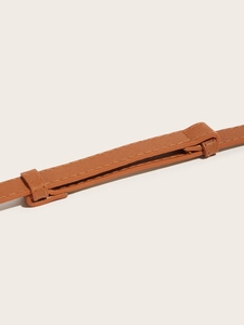 Macro detail of brown Saffiano leather belt featuring refined cross-grain texture and edges