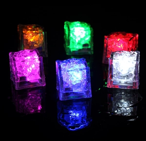 Macro shot of 6 pieces multi-color LED glowing ice cubes with reflections on a wet surface