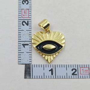 Macro shot showing dimensions of gold heart evil eye pendant necklace on tape measure