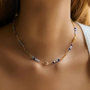 Detail of bohemian necklace with multi-colored beads and gold-plated heart elements