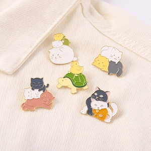 Detail view of colorful enamel cat and turtle stack pins on velvet fabric background