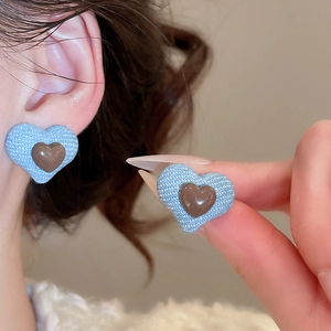 Close-up of blue denim texture heart earrings with a polished brown resin center detail