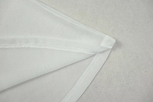 Detailed close-up of white chiffon fabric edge with professional overlock stitching detail