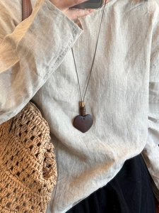 Detail of a minimalist wooden heart pendant necklace with a vintage brown cord strap