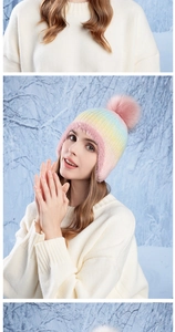 Detailed close-up of rainbow gradient knit hat with pink faux fur trim and pom-pom