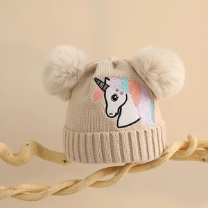 Detail der Strickstruktur und weichen Bommel an einer beigen Einhorn-Wintermütze