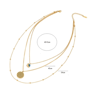 Detail showing S.STEEL stamp on gold triple-layer evil eye necklace with three chain lengths