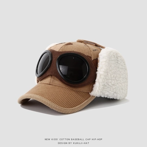 Macro view of brown corduroy kid's baseball hat with pilot goggles and warm earflaps