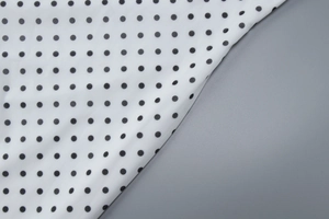 Macro detail of white fabric with black polka dots showing smooth textile texture