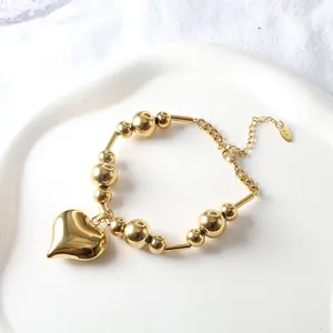 Detail of 18k gold plated stainless steel bead heart bracelet on ceramic tray