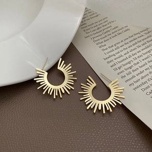 Chic golden sunburst fan-shaped earrings on a brown surface with elegant props