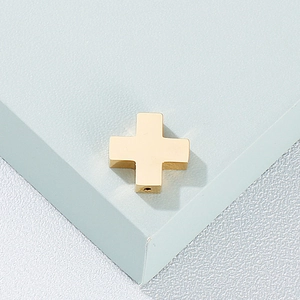 Close-up of golden stainless steel cross pendant on a modern blue geometric block