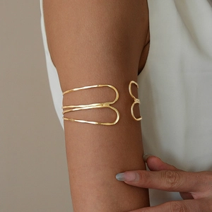 Detailed close-up of a minimalist gold layered cross cuff bracelet on a model's wrist