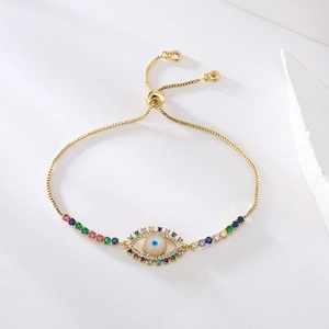 Detailed shot of gold evil eye bracelet with colorful cubic zirconia and slider clasp
