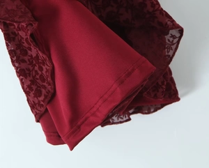 Macro detail of wine red lace fabric with silk lining and reinforced stitching finish