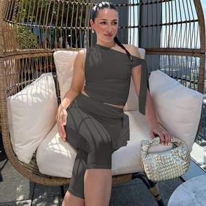 Outdoor lifestyle shot of a model in a dark gray one-shoulder top and tight shorts set
