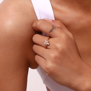 Detailed close-up of a gold flower ring with zircon stones worn by a model