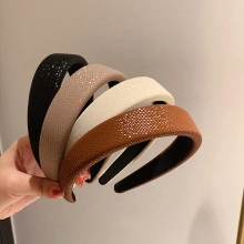 Close-up of four textured leather-style headbands in black, beige, white, and brown