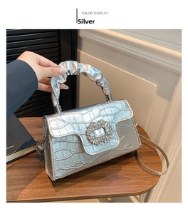Détail du sac argenté gaufré crocodile avec boucle en strass et poignée plissée