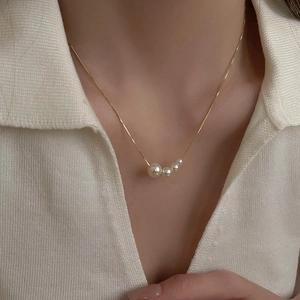 Gros plan détaillé d'un collier pendentif en perles dorées porté sur une femme
