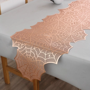 Detailed macro view of rose gold spider web table runner with metallic hollow-out design