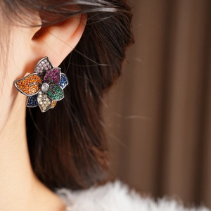 Close-up of a model wearing vintage floral stud earrings set with colorful zircon stones