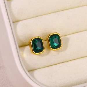 Close-up of emerald green square-cut earrings in gold setting on velvet jewelry box