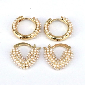 Detailed macro view of geometric gold earrings featuring pavé pearl clusters and heart shapes