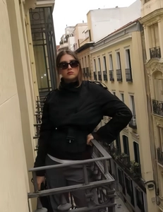 Detail of short black trench jacket with collar and belt buckle on outdoor balcony
