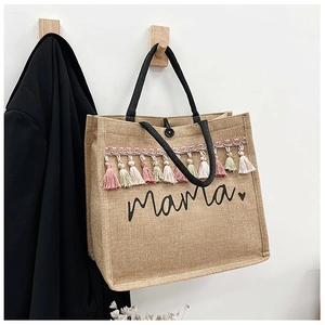 Detail of linen tote bag with colorful tassels and Mama heart print on white background