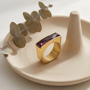 Detailed macro of a rectangular purple gemstone set in a brushed gold geometric ring band