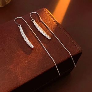 Dettaglio di orecchini a catena d'argento con zirconi su una scatola di pelle
